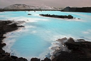 bright blue hotsprings surrounded by dark volcanic rock in Iceland