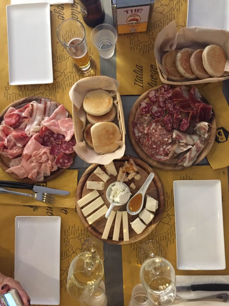 an overhead view of a table with meat, cheeses and breads in bologna Italy