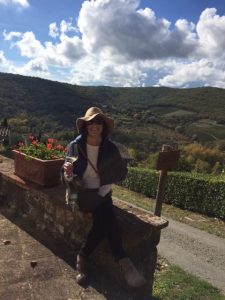 a smiling honeymooner on a wall with beautiful rolling Italian hills 