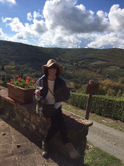 a smiling honeymooner on a wall with beautiful rolling Italian hills