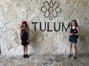 two girls pose next to the Tulum sign in Mexico
