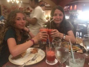 two young girls cheers their blended drinks with heart straws in Cancun