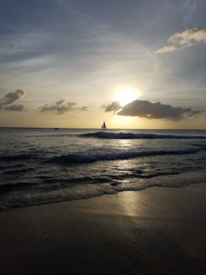 beach sunset with sailboat on horizon