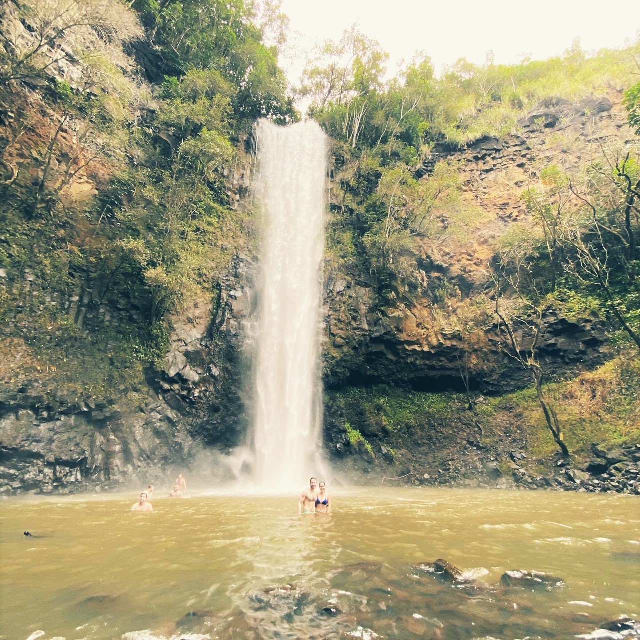 couple in the pool of a large waterfall Hawaii