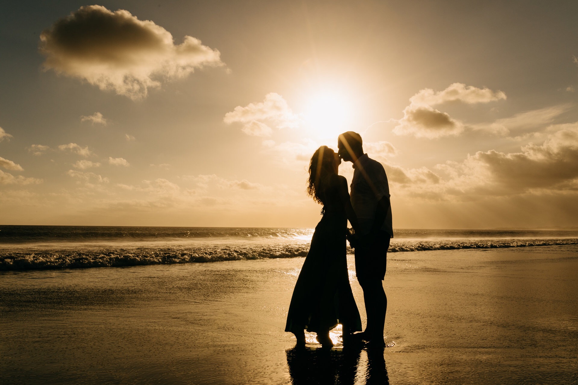 Honeymooners kiss on a beach sunset