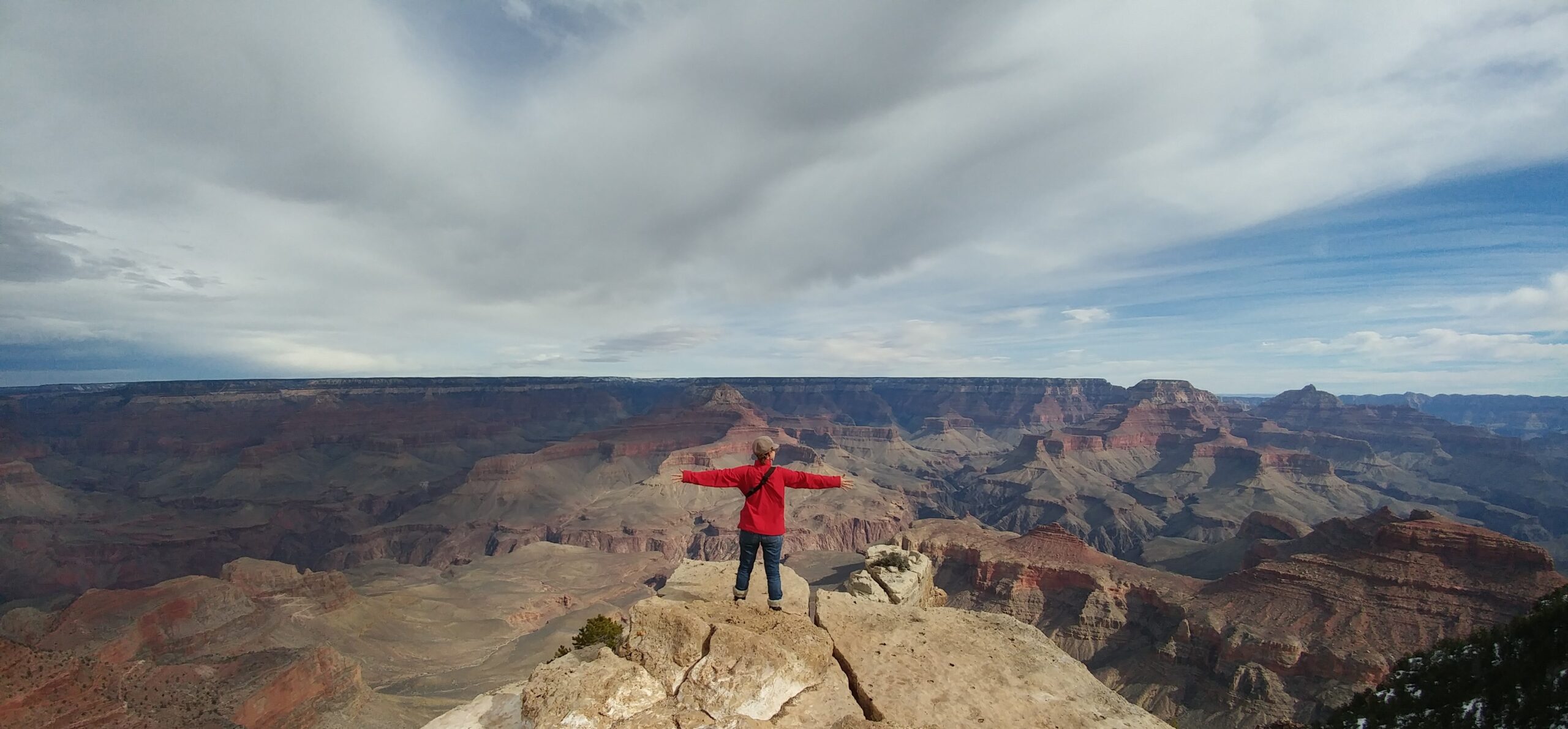 woman at the edge of a overhand looking at the vast grand canyon