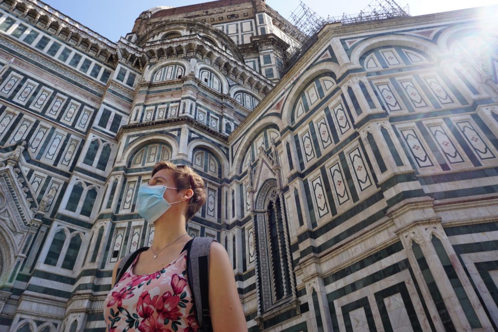 a woman with a facemask on outside Il Duomo in Florence Italy