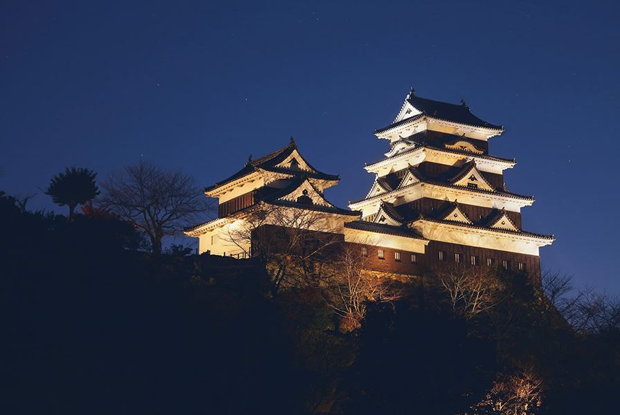 A japanese castle lit up at night in the Setouchi region of Japan