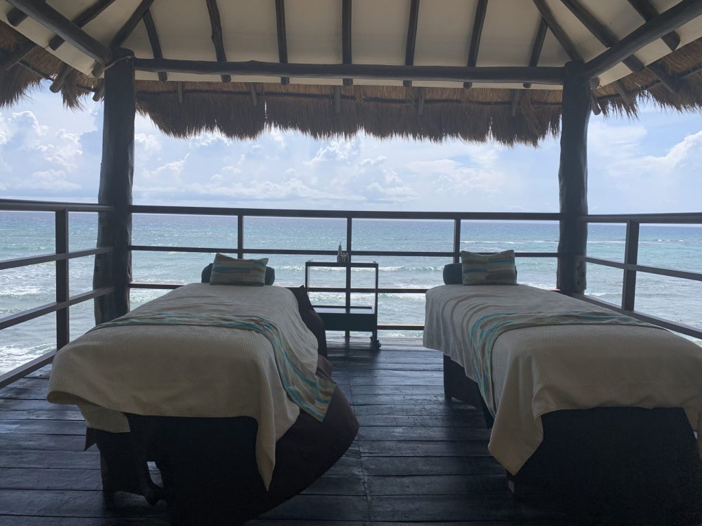 two massage beds in a thatch-roofed hut on the beach in Mexico