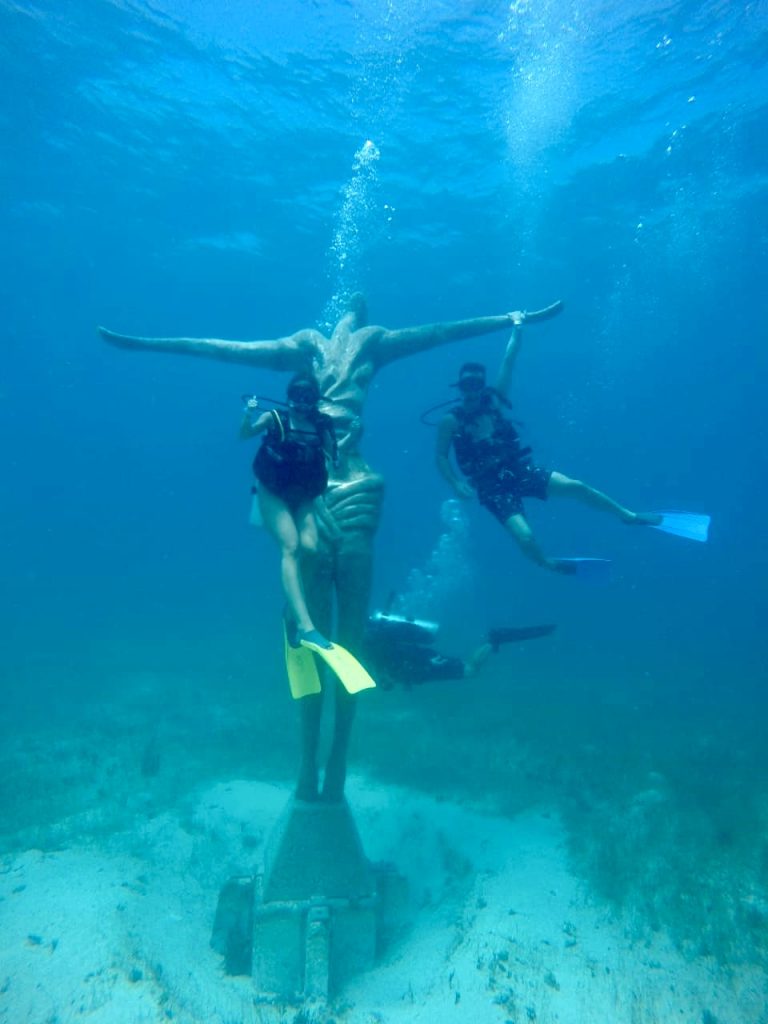 two scuba divers with an underwater sculpture in Mexcio
