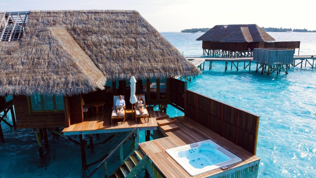 a couple sitting on the back terrace of their overwater bungalow with private jacuzzi and direct access to the sea in the Maldives