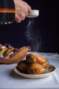 a hand dusts powdered sugar on round pasteries in Slovenia
