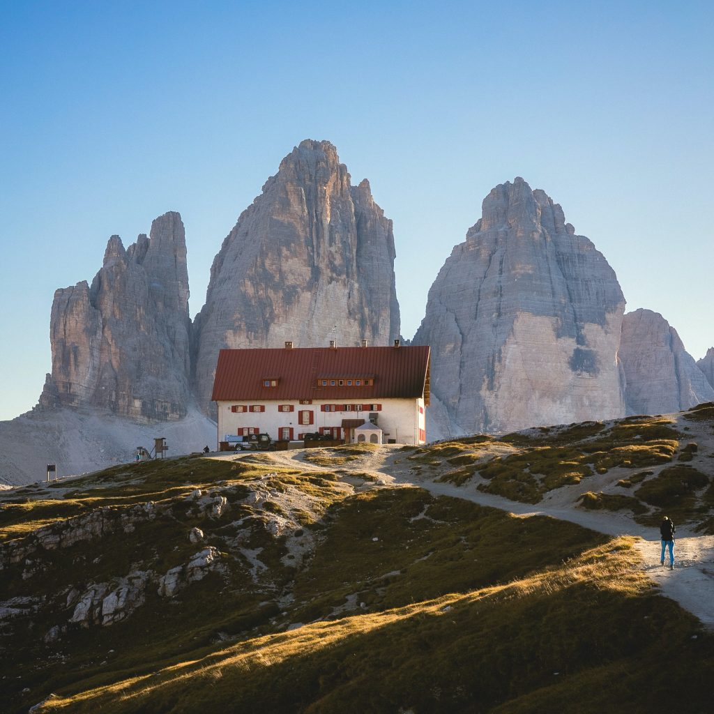 three imposing mountain spires behind a inn on a hill in the Dolomites
