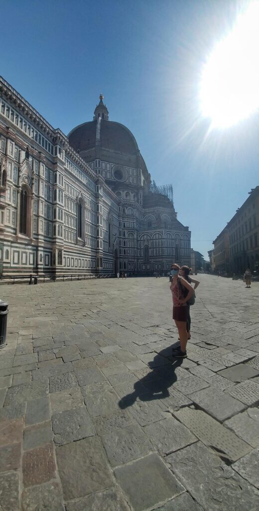 a woman standing practically alone in Piazza del Duomo with the Florence Duomo in the background