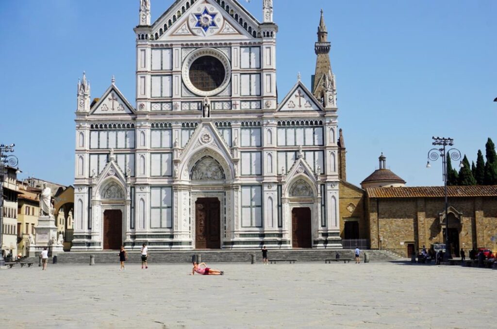 a woman lays down in an almost empty courtyard in front of Santa Croce Florence Italy
