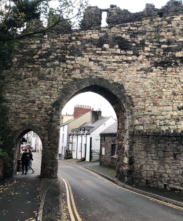 an old stone arch with a road running through it in Conwy Wales