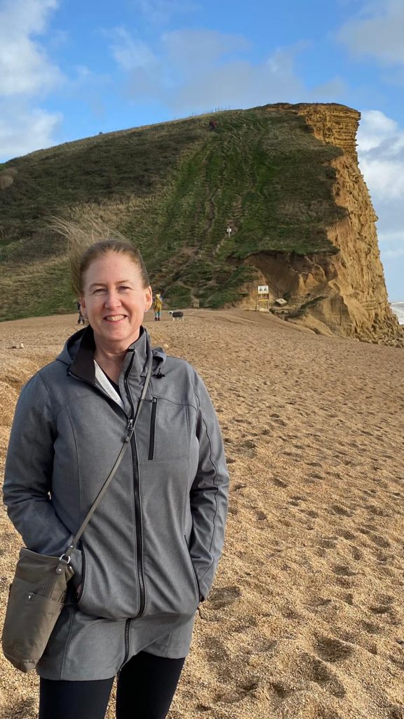 A smiling Ann on the sandy beach of the Dorset Coastline UK