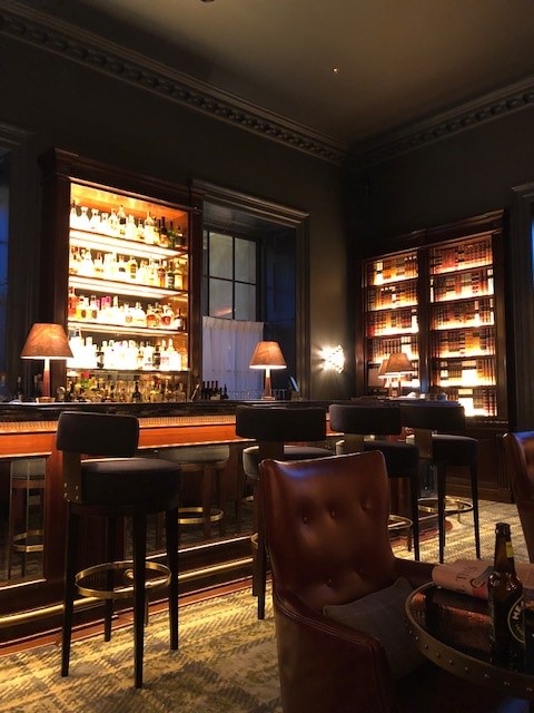 an atmospheric english bar with backlit shelves and small table lamps at Langley hotel in UK