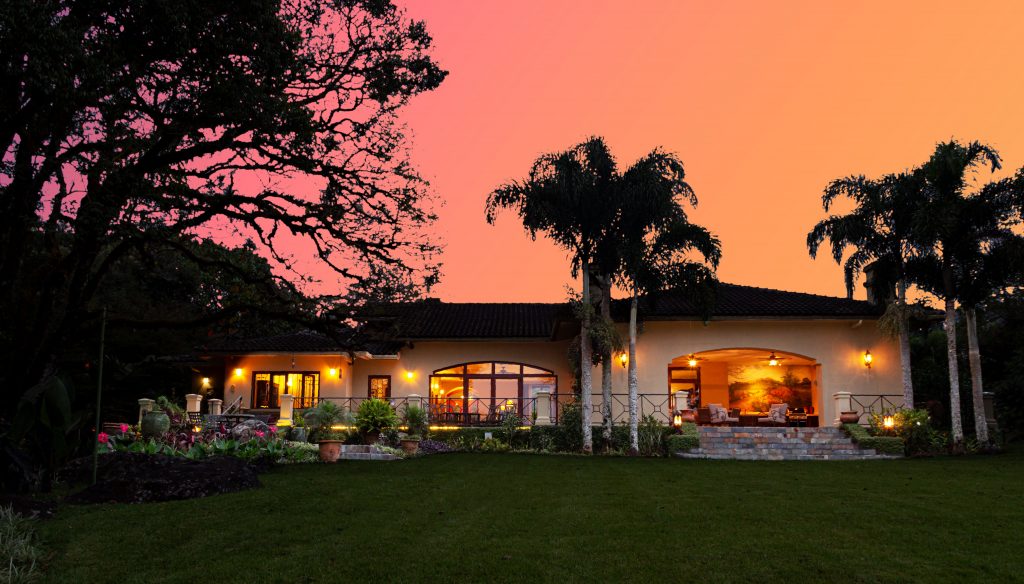 a sprawling villa framed by the pink and orange of a beautiful sunset