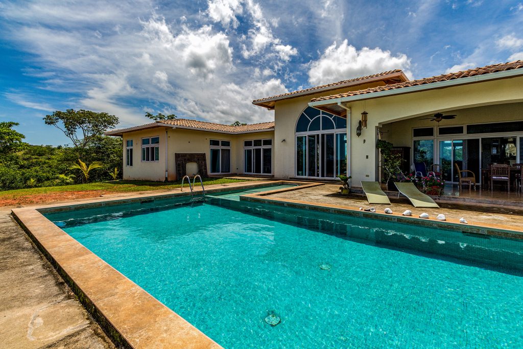 a bright blue pool at the back of a large house in Panama