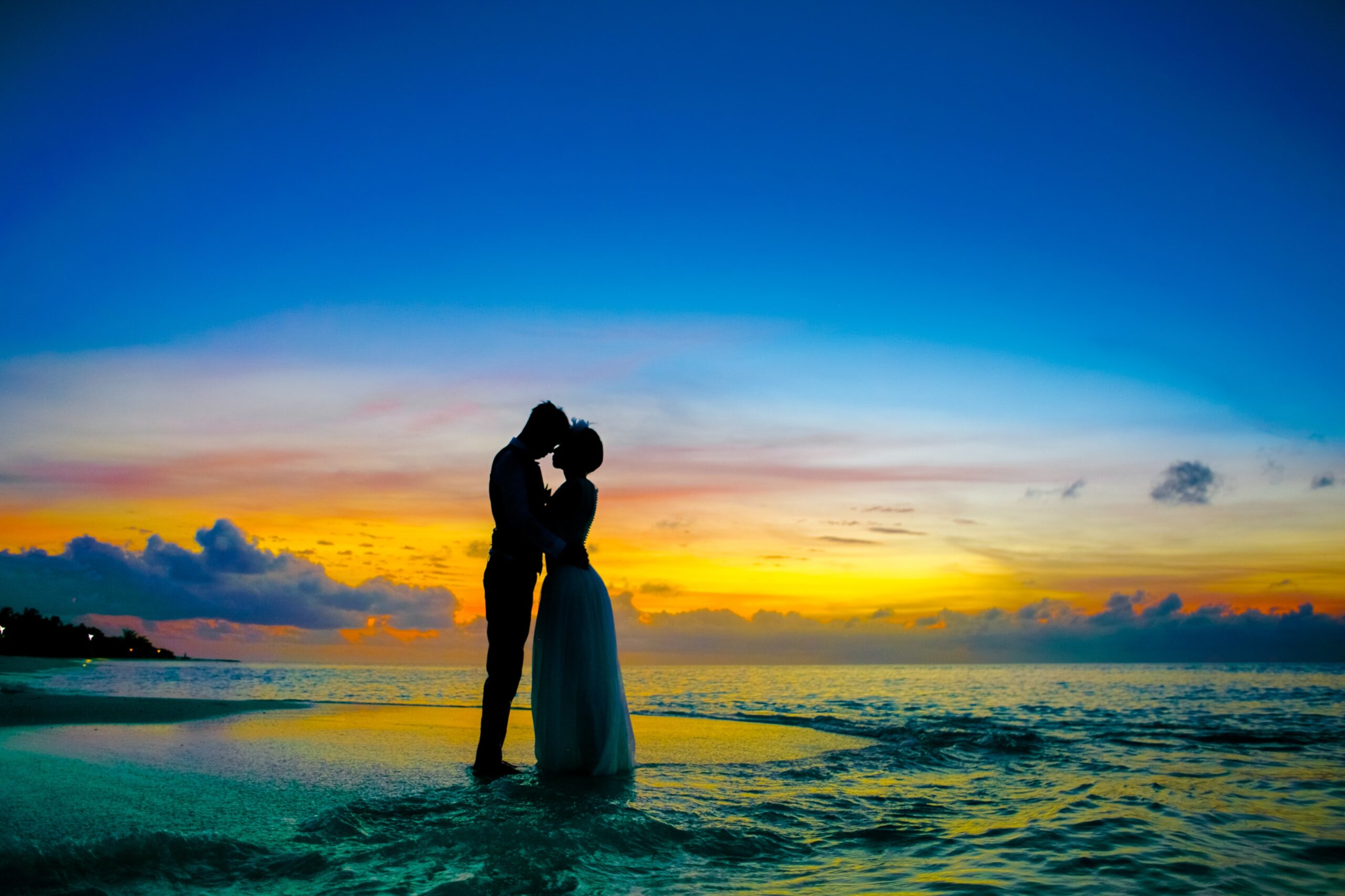 A honeymoon couple close together on a beach at sunset in the maldives