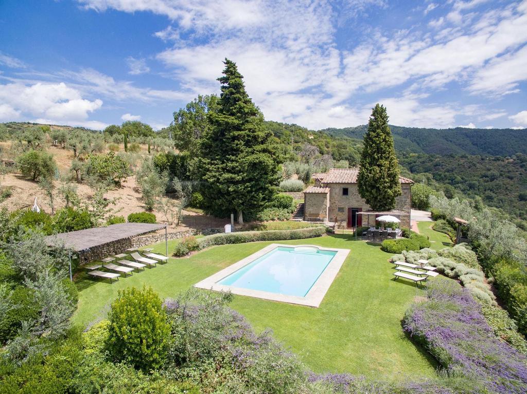 Buccelletti Casale and Cantina pool, lounge chairs and stone building surrounded by the green hills of Tuscany