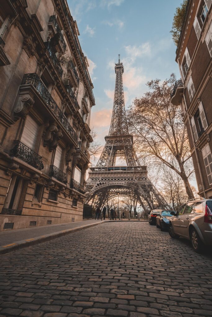 a bricked street with luxury buildings and the Eiffel Tower at the end in Paris