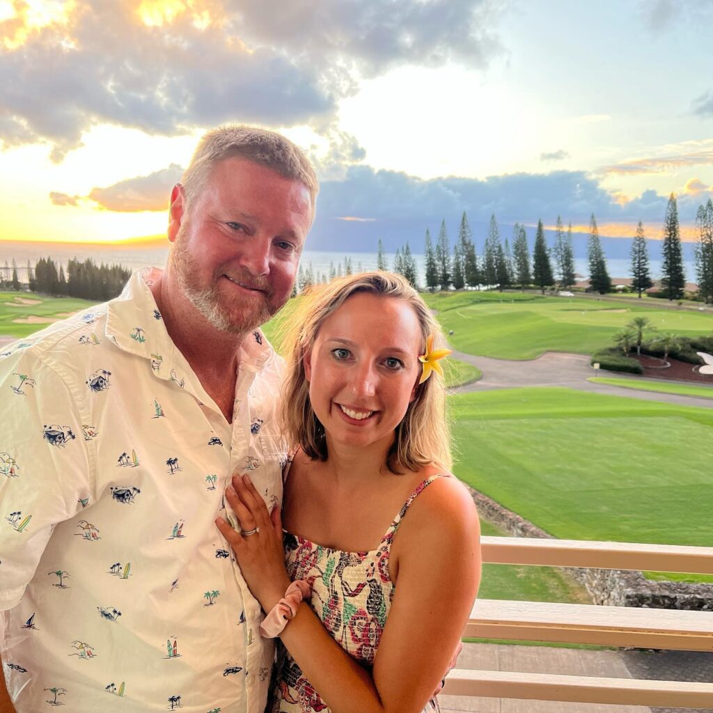 a couple in Hawaii on their honeymoon with green lawns and sunset in the background