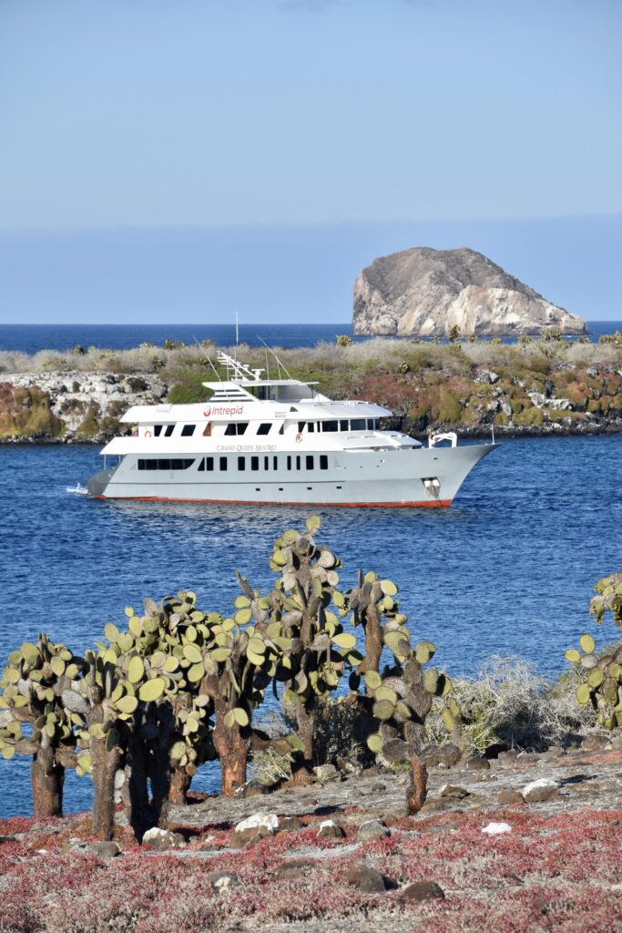 The Queen Beatriz yacht floating between two islands of cacti in the Galapagos