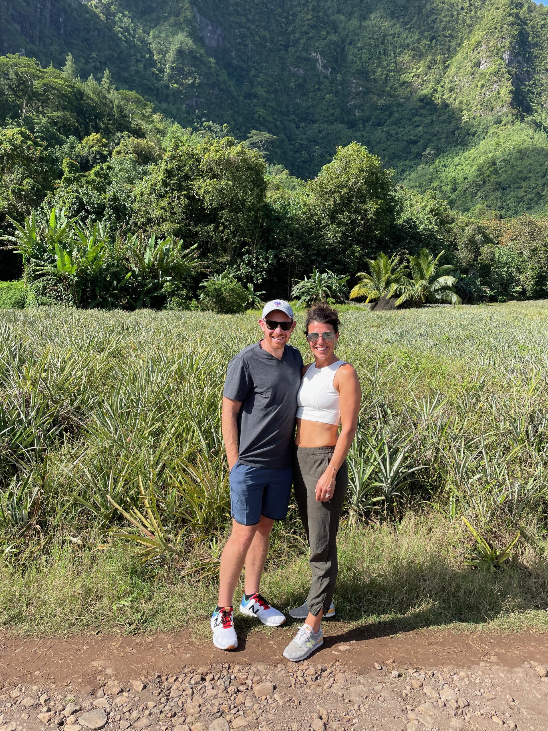 Tahiti - a honeymoon couple in front of a pineapple field with green mountains in the background in Tahiti