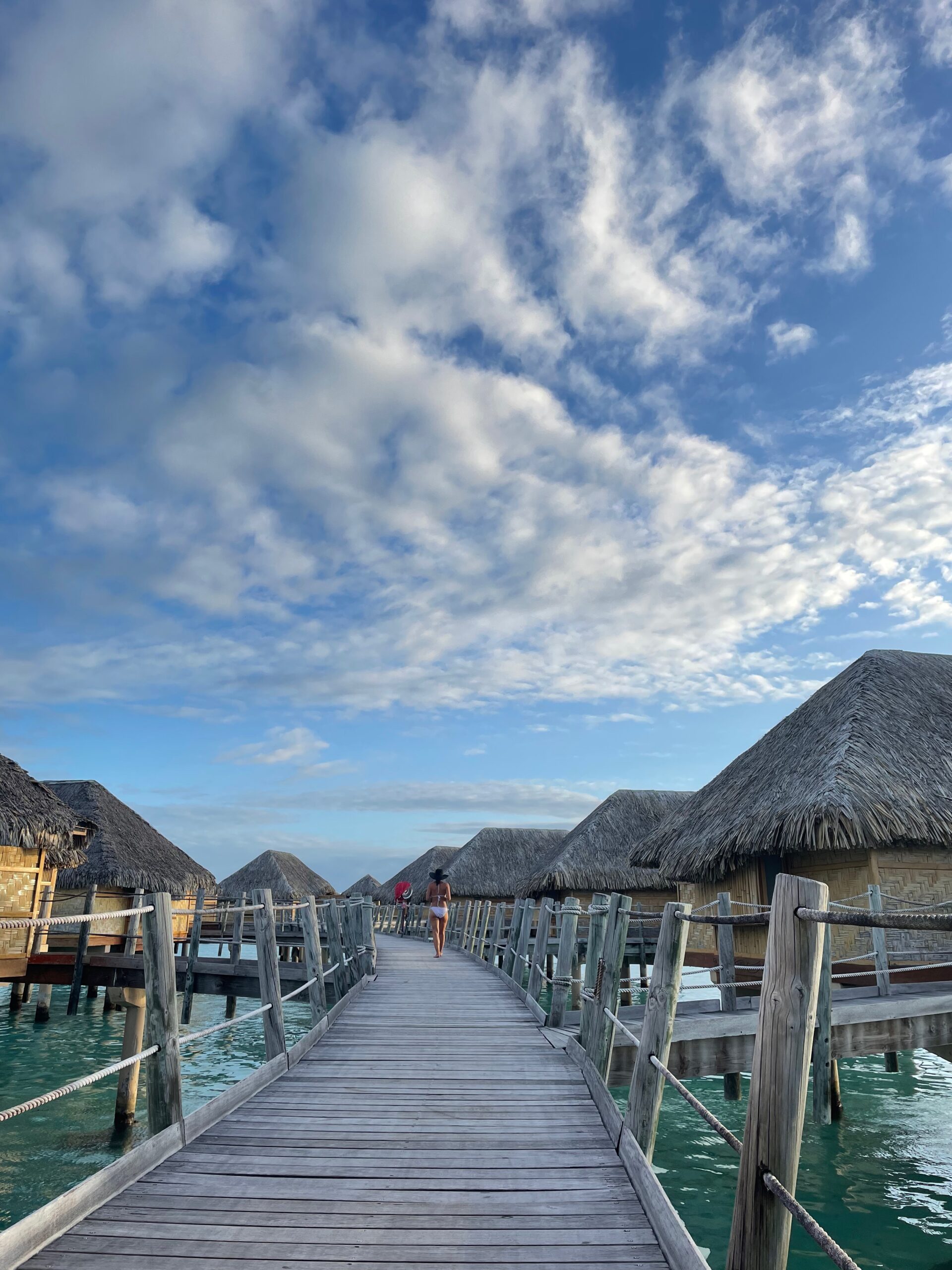 looking down the walkway of a series of overwater bungalows in Taha'a  for a Tahiti honeymoon